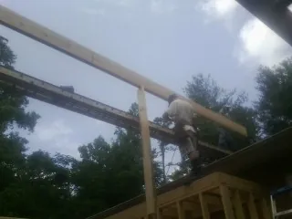 Carpenter setting a ridge beam over a new addition frame — Ice Dam Removal by Roofing Brothers in Lolo