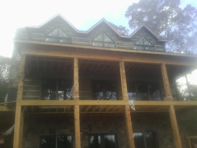 Dormers and porch framing on a large log home under construction — Roof Coating work by our crew in Lolo