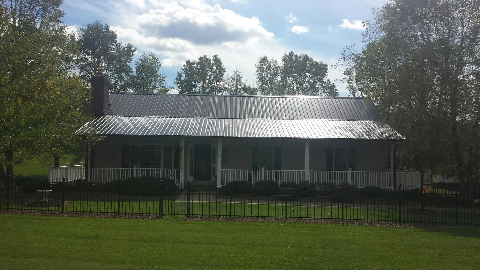 Gray metal roof on a brick ranch with a full width front porch — Gutter Guard Installation work by our crew in Lolo