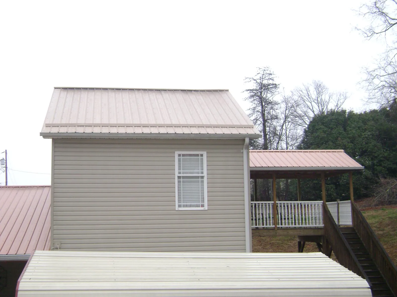 Tan metal roofs on a two story addition and attached porch, from a Roof Replacement job in Lolo